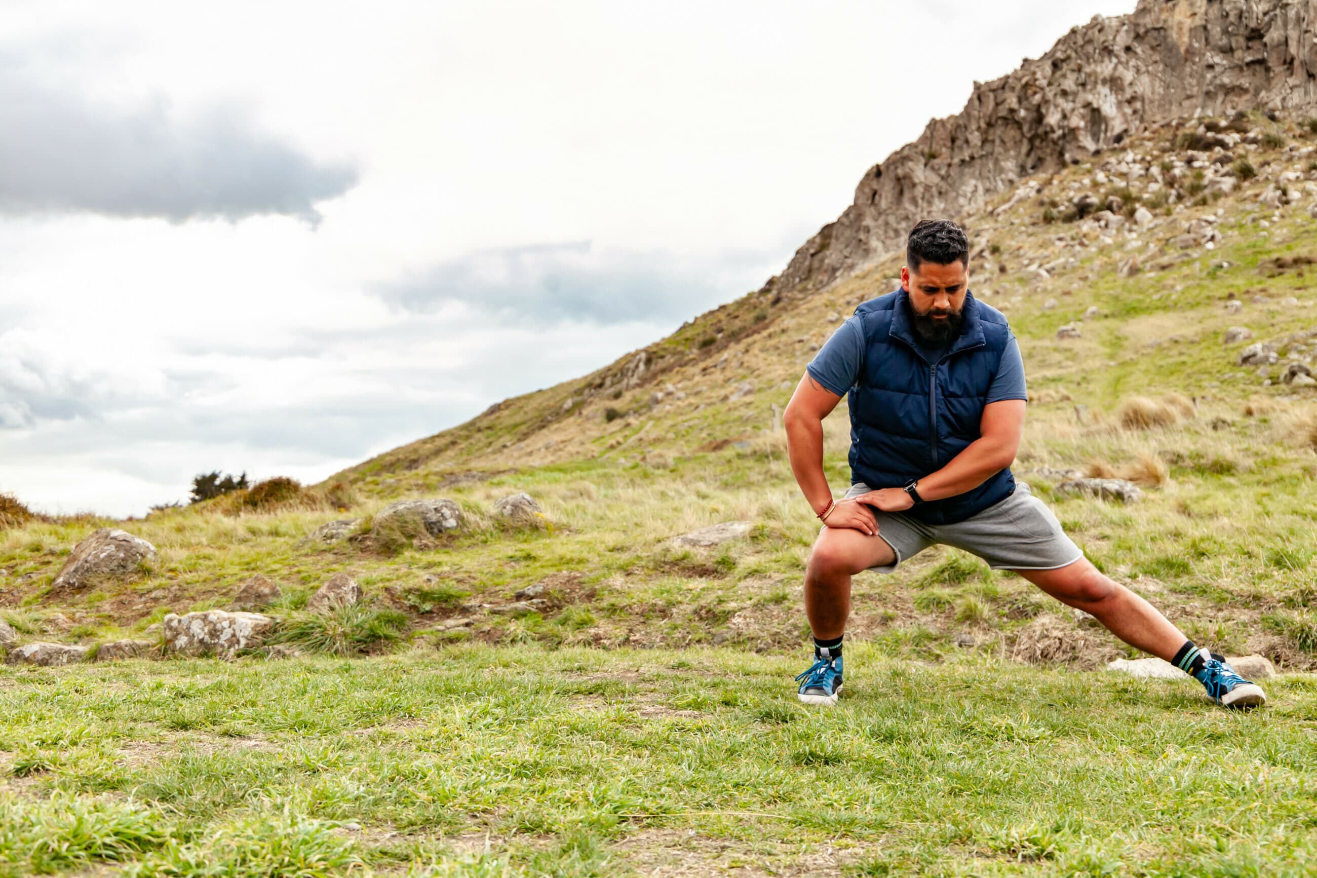A man stretching outdoors on a NZ hillside